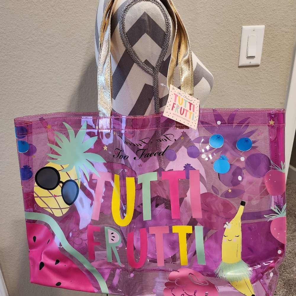 New with tag. Too Faced Tutti Frutti clear vinyl tote bag. Pink with gold strap.
